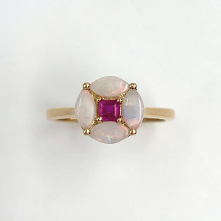 BAGUE circulaire en or jaune (750) serti d'un rubis entouré de quatre opales ta…