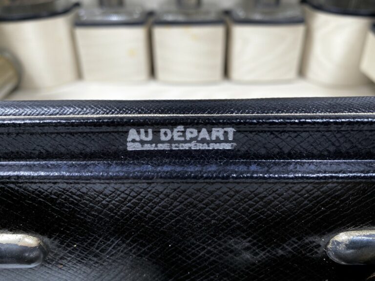 Valise en cuir noir grainé siglée "Au départ, 29 avenue de l'Opéra, Paris" cont…