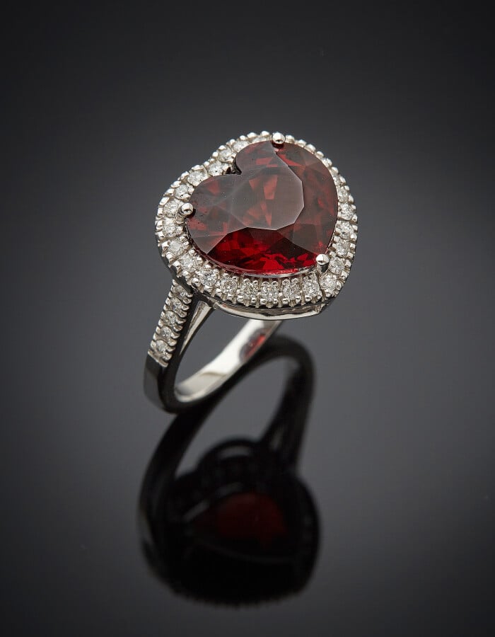 BAGUE « coeur » en or gris (750) serti d'un grenat pyrope, taillé en coeur, ent…