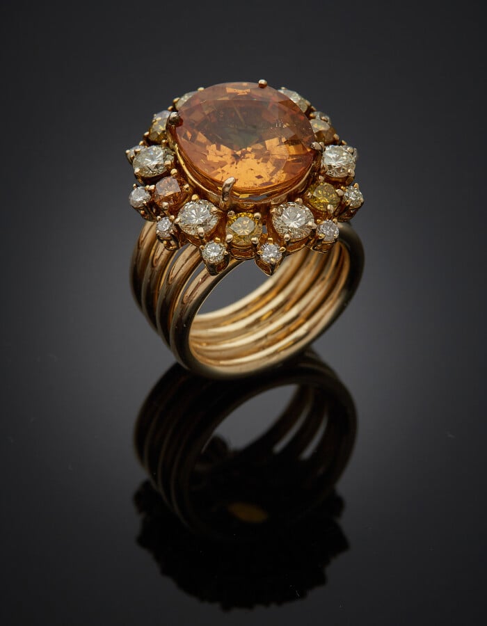 BAGUE "marguerite" en fils d'or jaune (750) serti d'un saphir jaune-orangé oval…