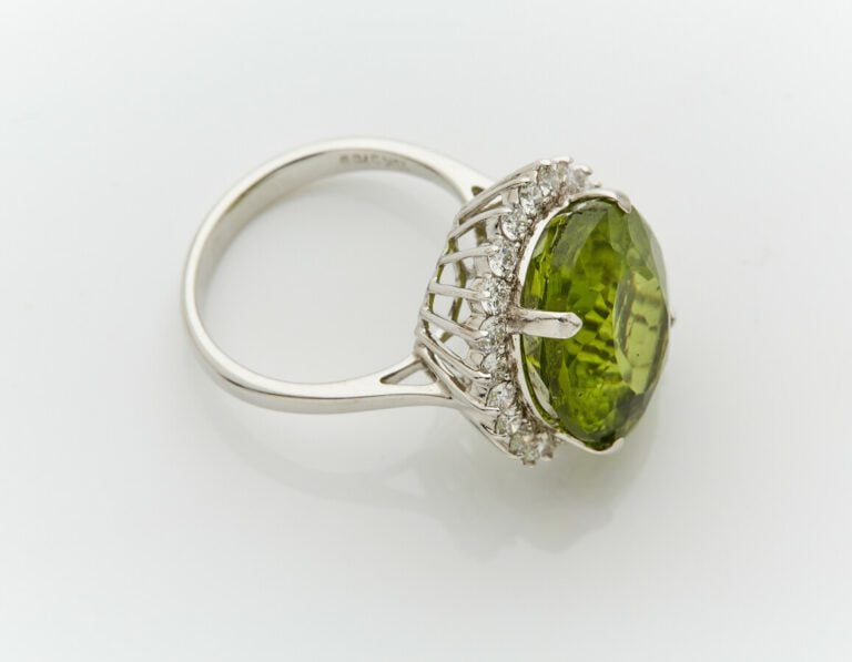 BAGUE "marguerite" en or gris (750) centré d'un péridot de forme ovale, entouré…