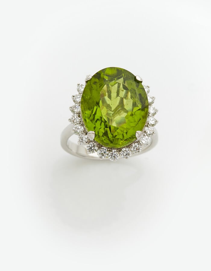 BAGUE "marguerite" en or gris (750) centré d'un péridot de forme ovale, entouré…