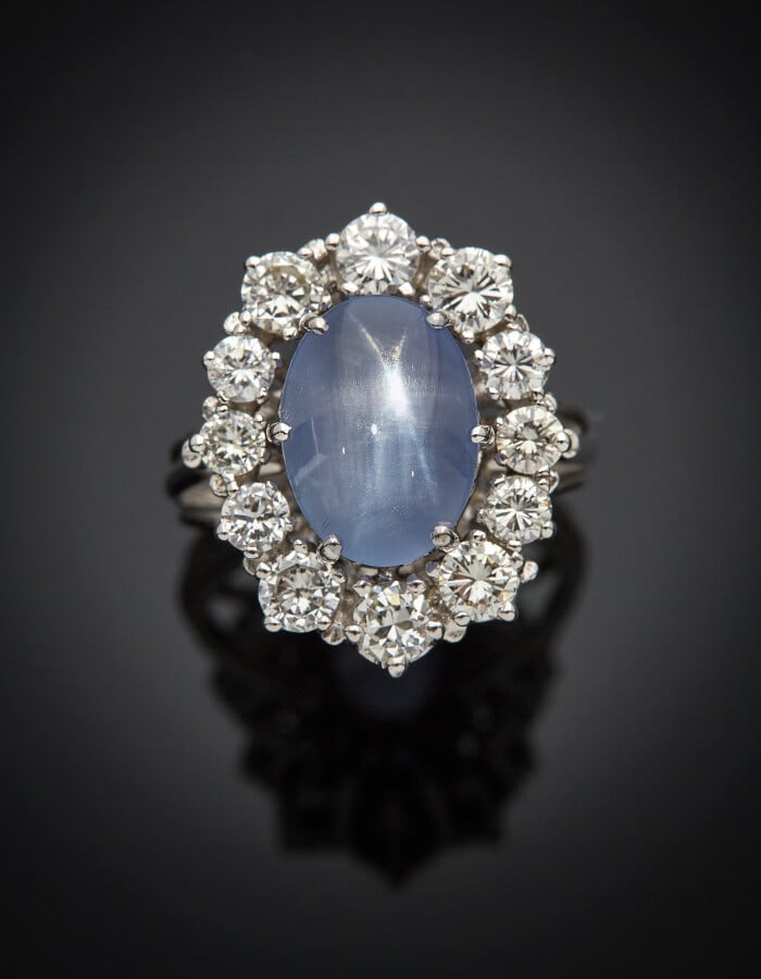 BAGUE "marguerite" en or gris (750) serti d'un saphir étoilé cabochon de forme…