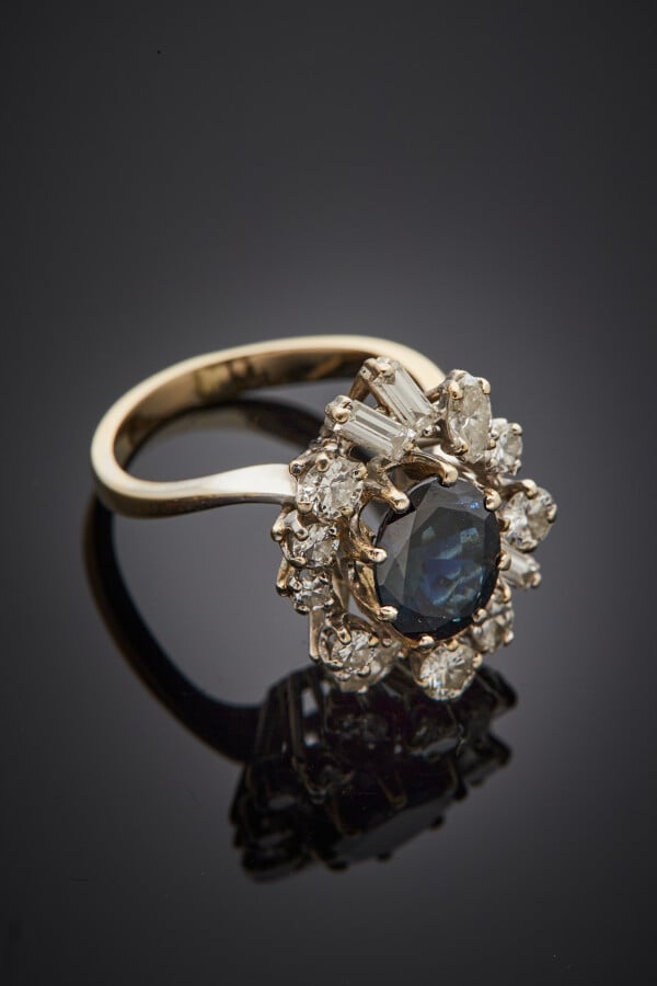BAGUE "marguerite" en or gris (750) serti d'un saphir foncé, entouré de diamant…