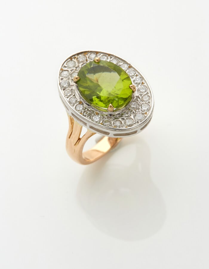 BAGUE ovale en or jaune et or gris (750) serti d'un péridot, entouré de diamant…