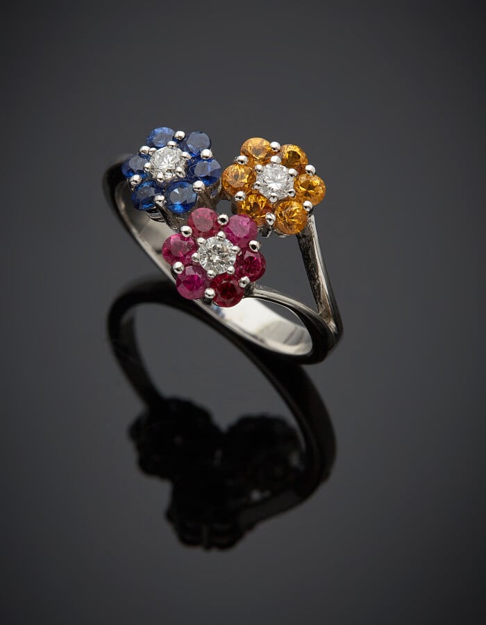 BAGUE "trois fleurettes" en or gris (750) serti de saphirs bleus et jaunes, rub…