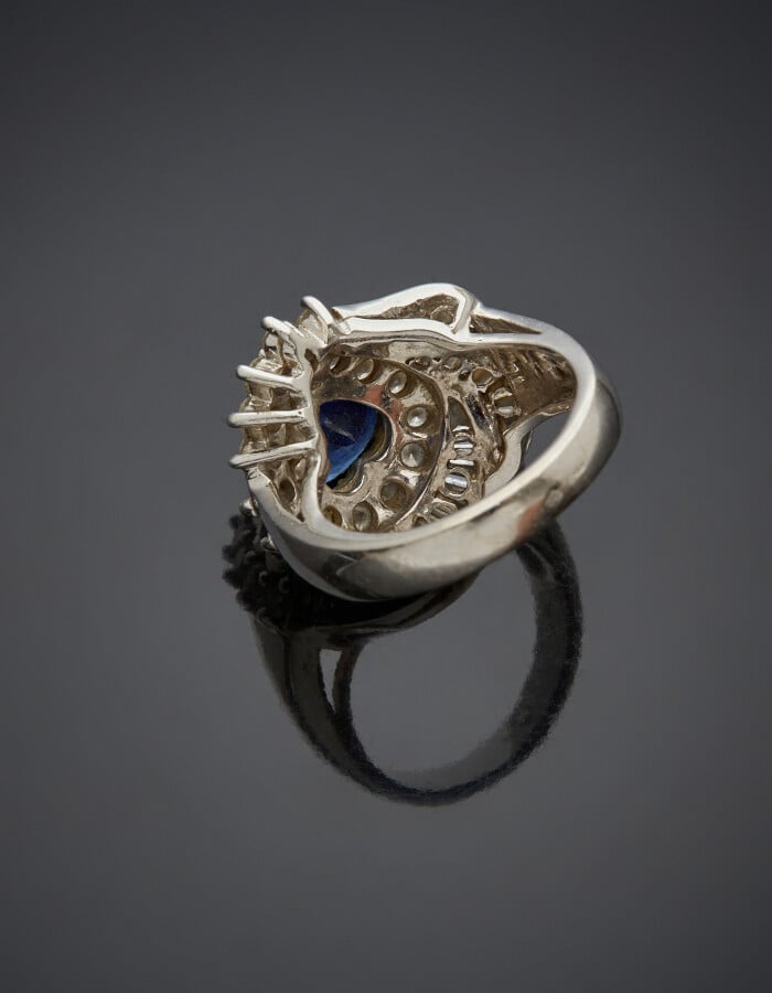 BAGUE "volutes" en or gris (750) serti d'un saphir taillé en coeur, entouré de…