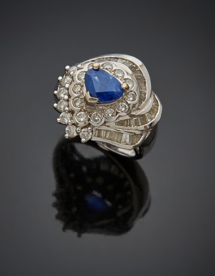 BAGUE "volutes" en or gris (750) serti d'un saphir taillé en coeur, entouré de…