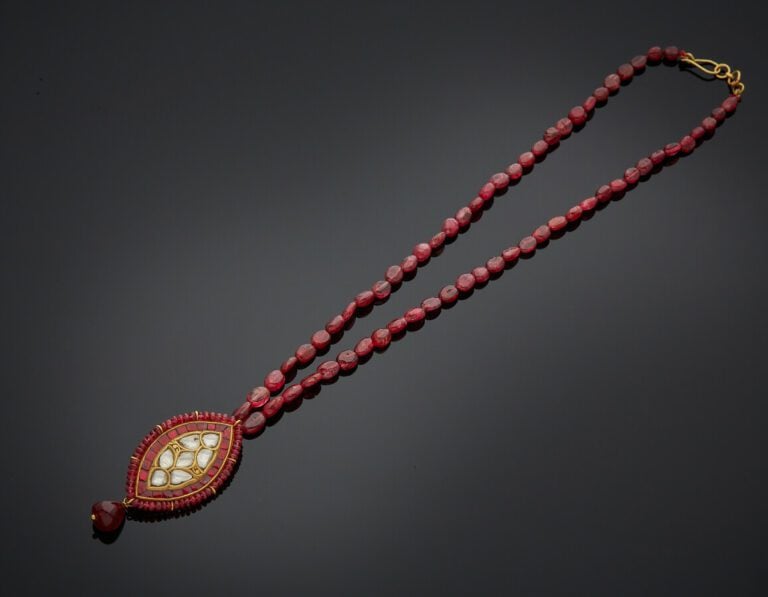 COLLIER composé d'un rang de perles de rubis ovales retenant un important pende…