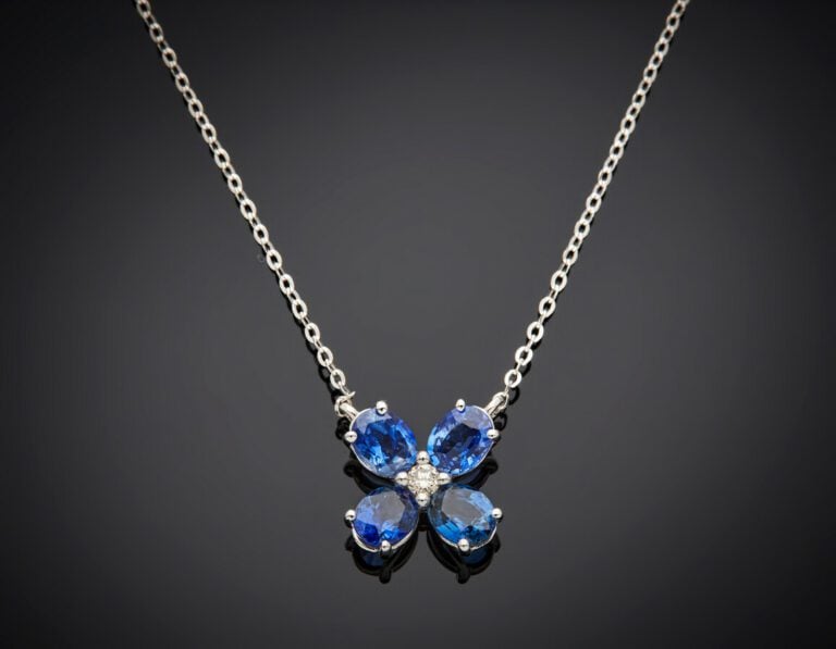 PENDENTIF « fleur » en or gris (750) serti de quatre saphirs ovales, centrés d'…