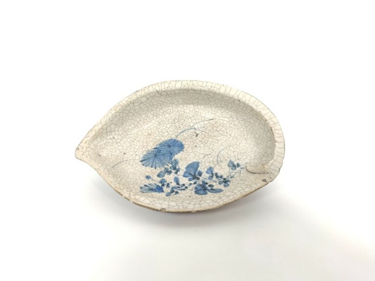 Une petite soucoupe en céramique craquelée en forme d'ormeau à décor en bleu so…