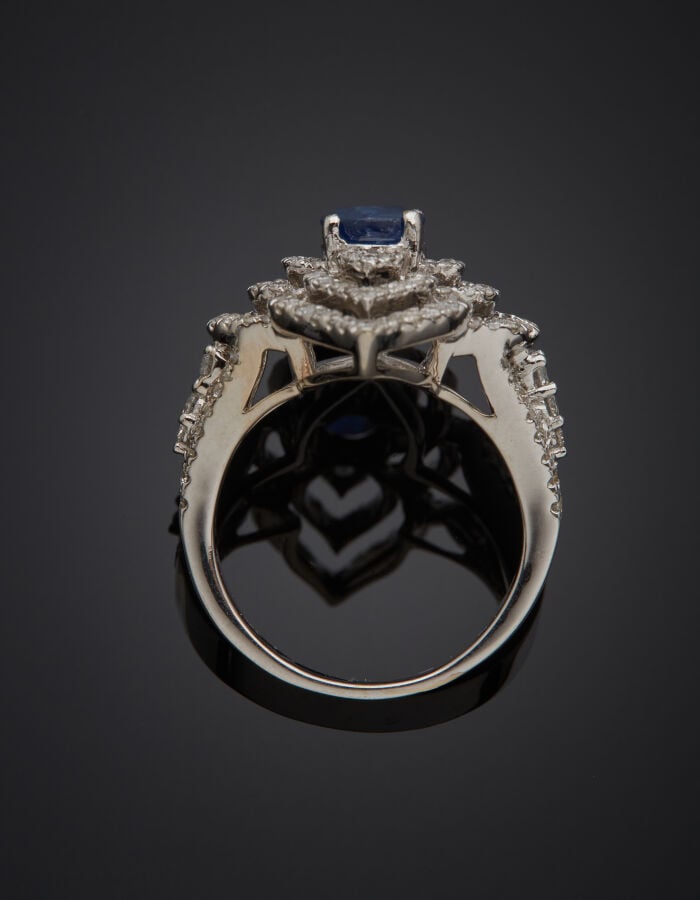 BAGUE "arabesque" en or gris (750‰) ajouré, serti d'un saphir, entouré de diama…