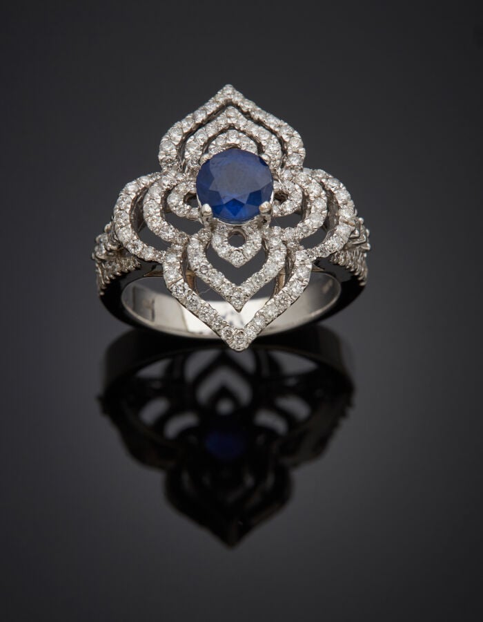 BAGUE "arabesque" en or gris (750‰) ajouré, serti d'un saphir, entouré de diama…
