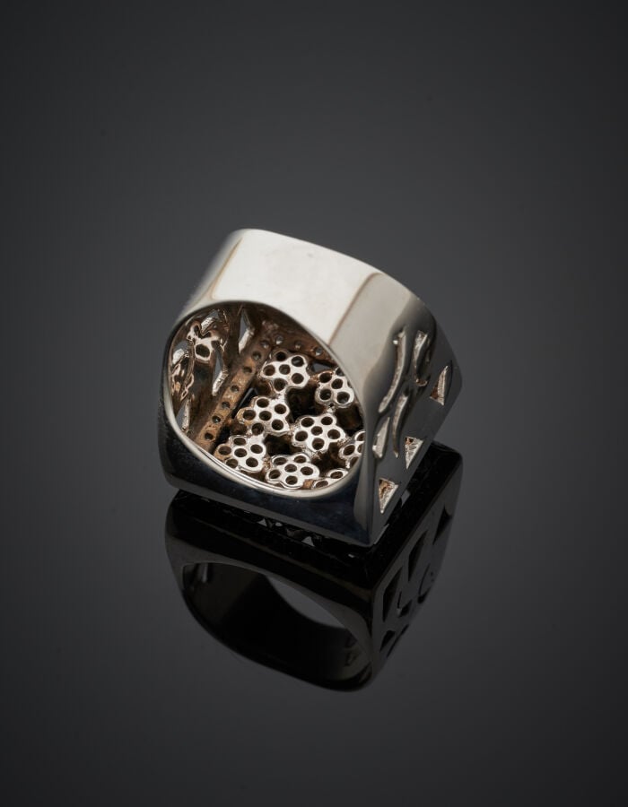 BAGUE "chevalière" carrée en or gris (750‰) ajouré, à motifs de neuf fleurettes…