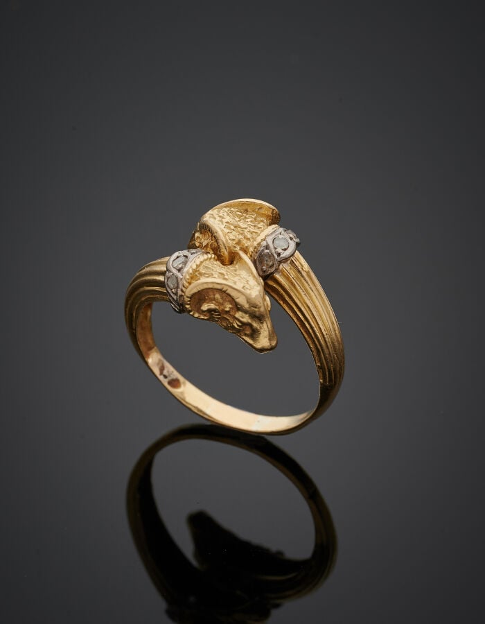 BAGUE "deux béliers" en or jaune et gris (750‰) ciselé, godronné, serti de diam…