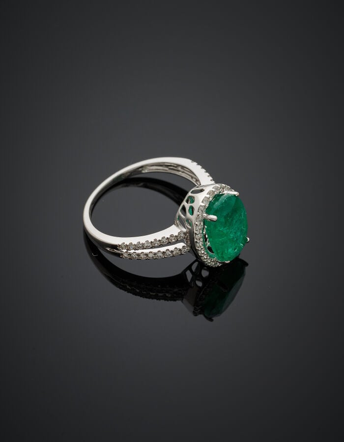 BAGUE en or gris (750‰) ajouré, serti d'une émeraude de forme ovale, entourée e…