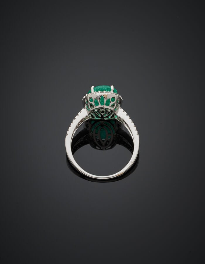 BAGUE en or gris (750‰) ajouré, serti d'une émeraude de forme ovale, entourée e…