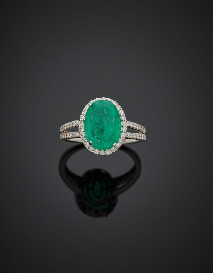 BAGUE en or gris (750‰) ajouré, serti d'une émeraude de forme ovale, entourée e…