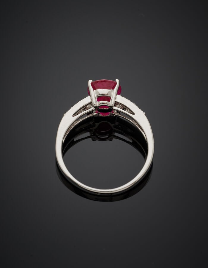 BAGUE en or gris (750‰) serti d'un rubis ovale, épaulé de six diamants taille b…