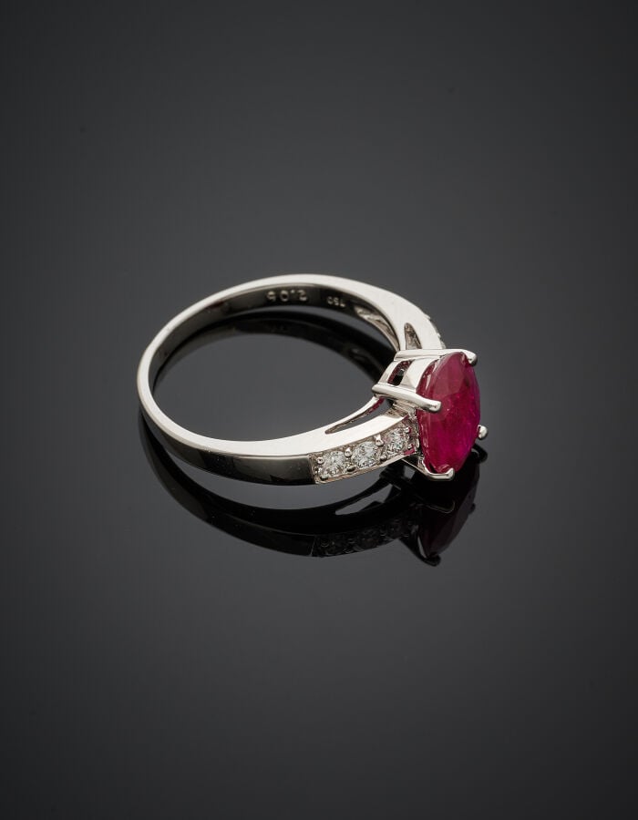 BAGUE en or gris (750‰) serti d'un rubis ovale, épaulé de six diamants taille b…