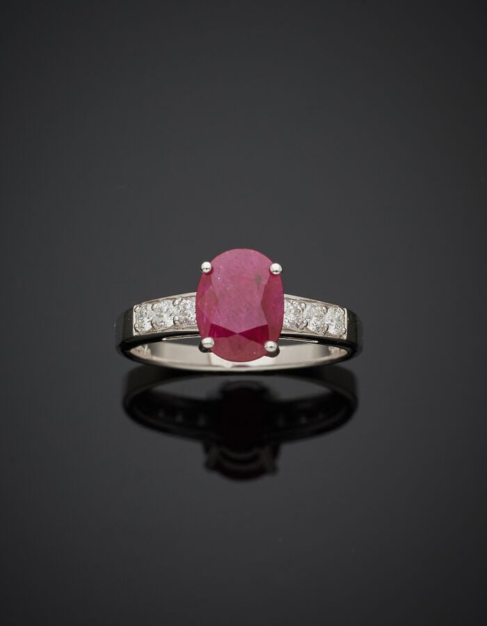 BAGUE en or gris (750‰) serti d'un rubis ovale, épaulé de six diamants taille b…