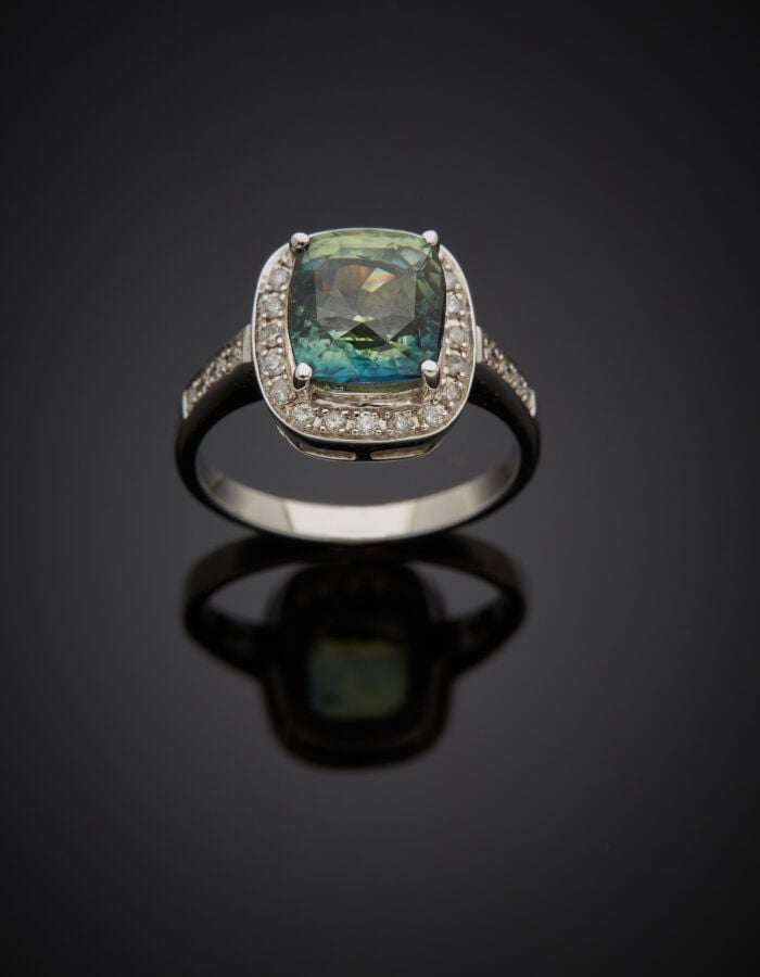 BAGUE en or gris (750‰) serti d'un saphir bleu-vert de forme cousin, entouré et…