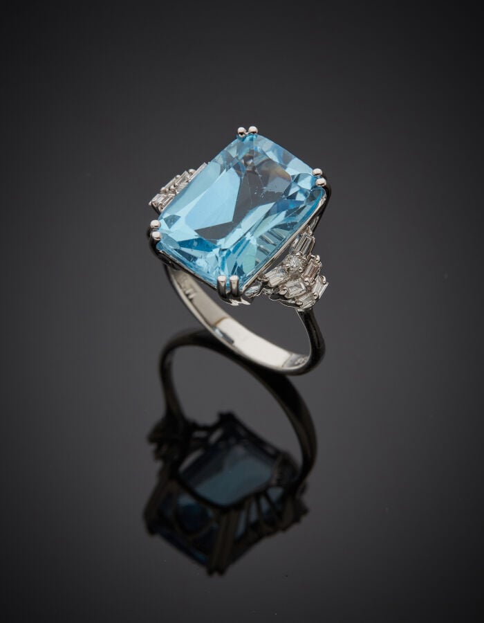 BAGUE en or gris (750‰) serti d'une topaze bleue de forme coussin, épaulée de d…