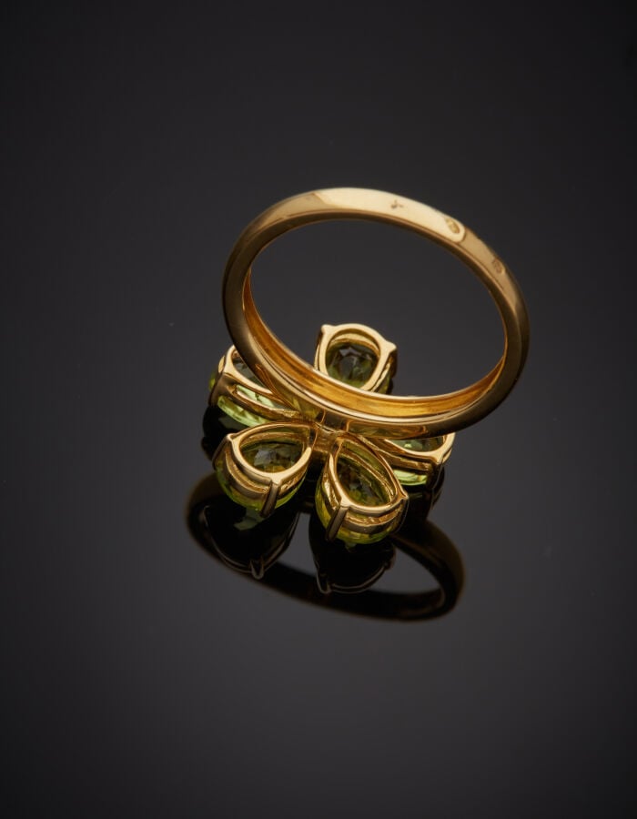 BAGUE "fleur" en or jaune (750‰) ajouré, serti de cinq péridots taillés en poir…