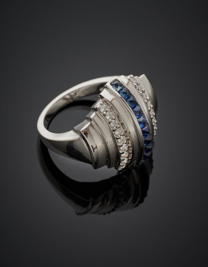 BAGUE géométrique en or gris (750‰) cranté, serti d'alignements de saphirs cali…