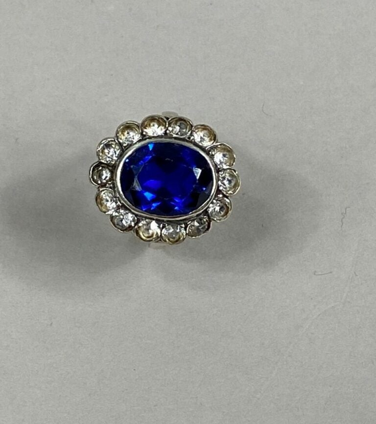 Bague marguerite en argent (925) ornée d'une pierre bleue ovale facettée dans u…