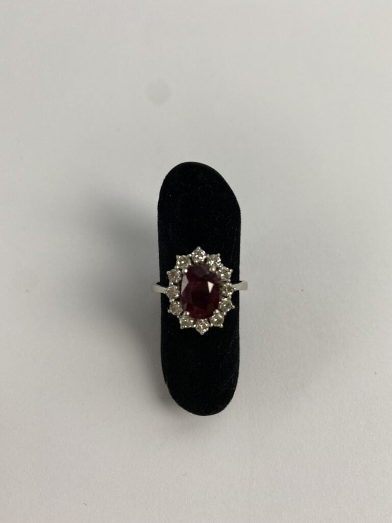 Bague marguerite en or gris (750) ornée d'un rubis de taille ovale facettée dan…