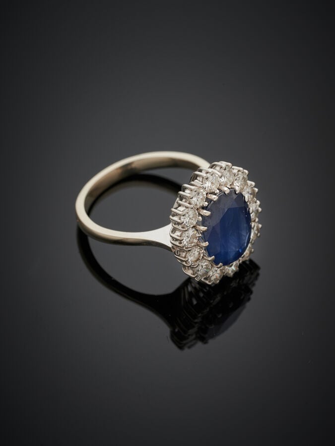 BAGUE « marguerite » en or gris (750‰) serti d'un saphir foncé de forme ovale e…