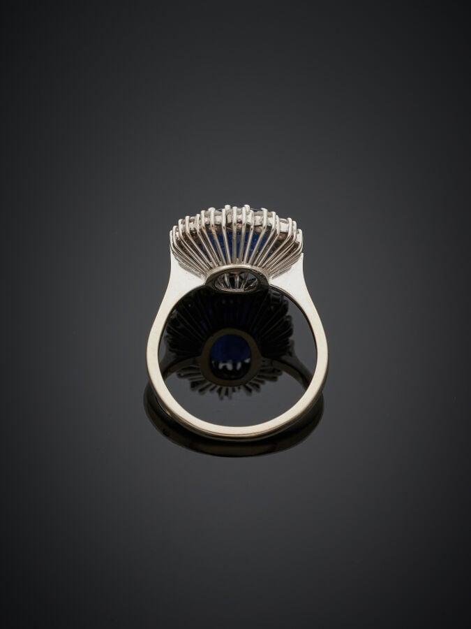 BAGUE « marguerite » en or gris (750‰) serti d'un saphir foncé de forme ovale e…