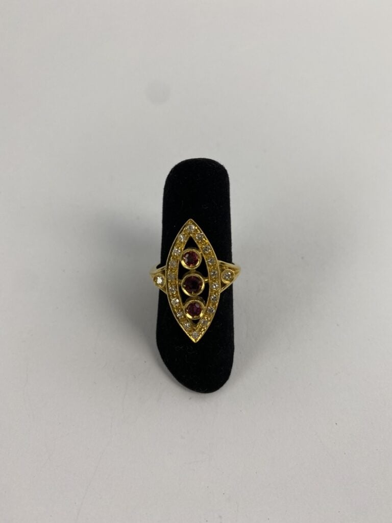 Bague navette en or jaune (750) ajouré ornée d'une ligne de trois rubis ronds f…
