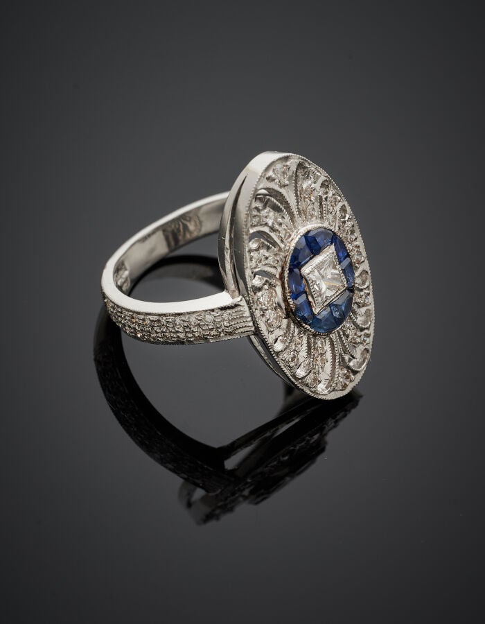 BAGUE ovale en or gris (750‰) ajouré à motifs de volutes, serti d'un diamant ta…