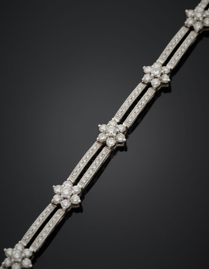 BRACELET articulé "dix fleurettes" en or gris (750‰) ajouré, entièrement serti…