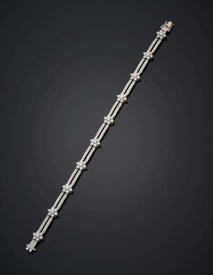 BRACELET articulé "dix fleurettes" en or gris (750‰) ajouré, entièrement serti…