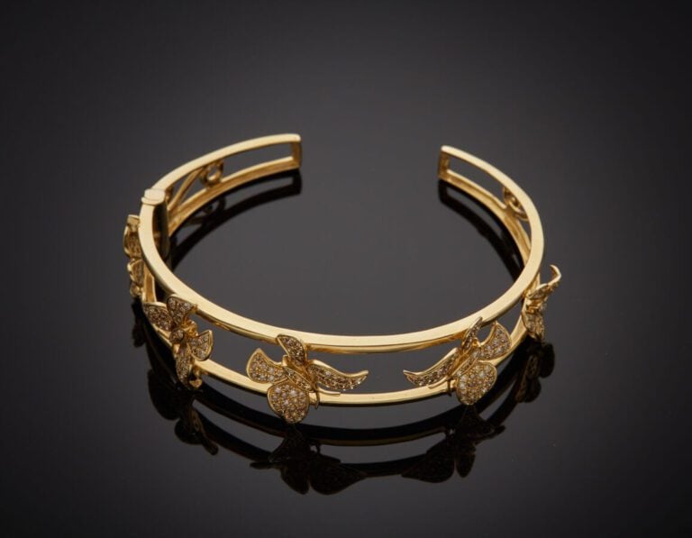 BRACELET "cinq papillons" rigide ouvrant en or jaune (750‰) ajouré, à motifs de…