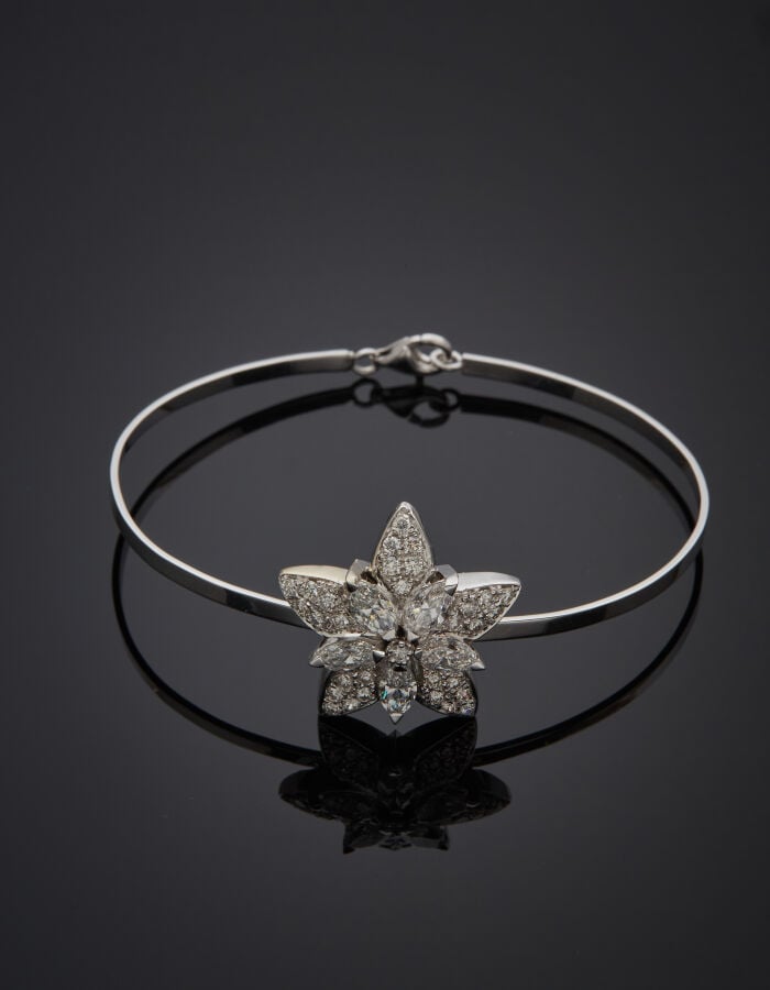 BRACELET rigide en or gris (750‰) surmonté d'un motif « étoile » serti de diama…