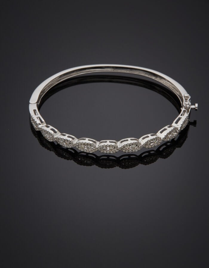 BRACELET rigide ouvrant en or gris (750‰) ajouré à motif tressé, serti de diama…
