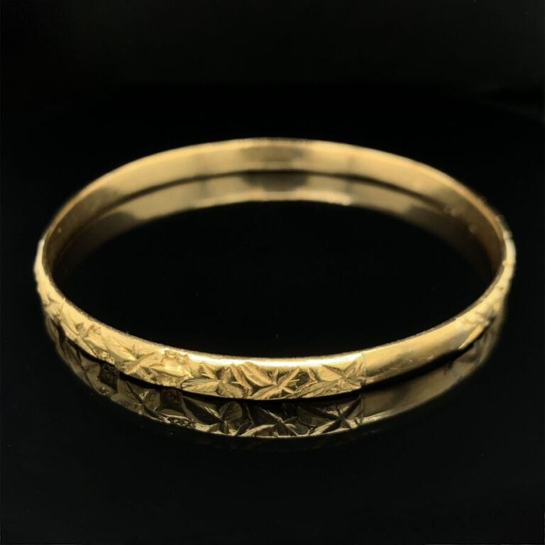 BRACELET rigide ouvrant en or jaune (750‰) ciselé à motifs de feuillage. Travai…