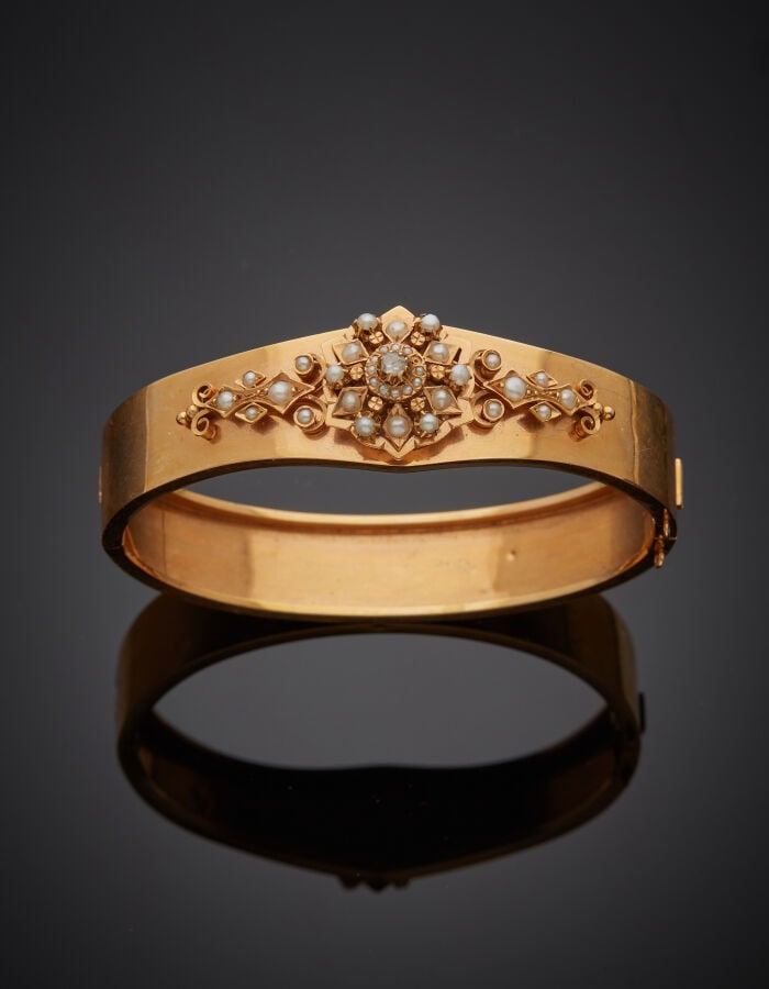 BRACELET rigide ouvrant en or rose (750‰) flanqué d'une rosace et volutes, sert…