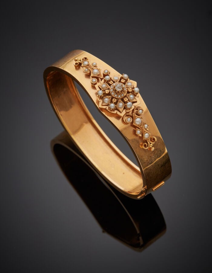 BRACELET rigide ouvrant en or rose (750‰) flanqué d'une rosace et volutes, sert…