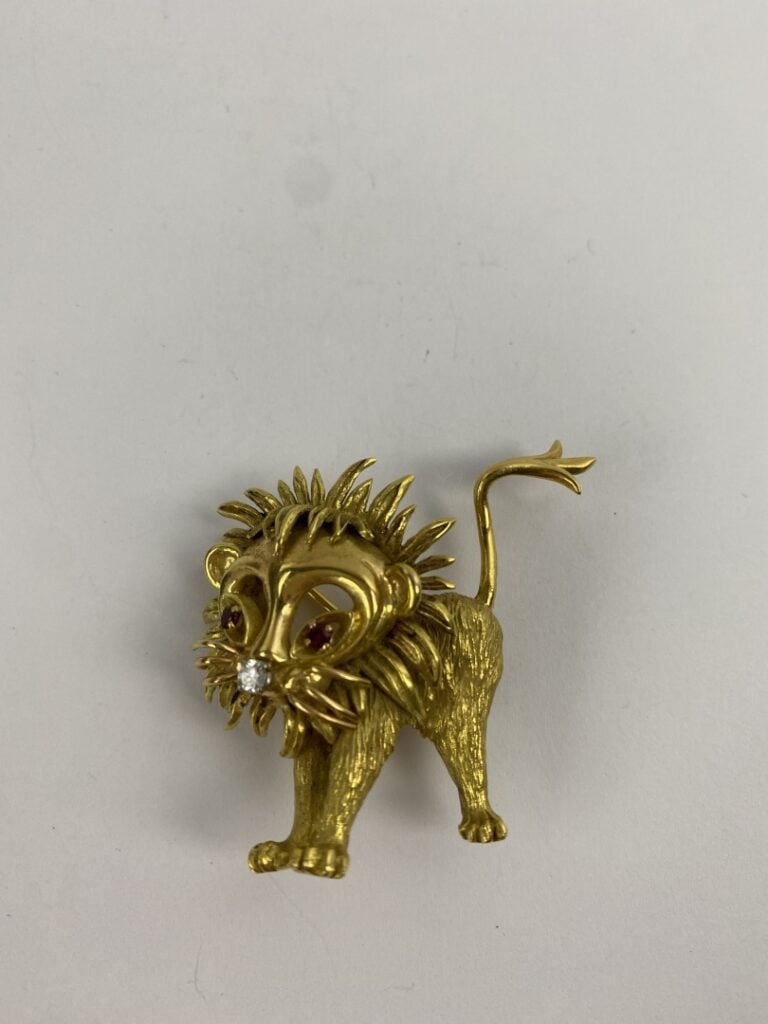 Broche Lion en or jaune (750) guilloché, la tête ajourée, le museau ponctué d'u…