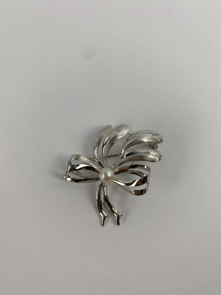 Broche noeud ajouré en or gris (750) partiellement amati centrée d'une perle de…