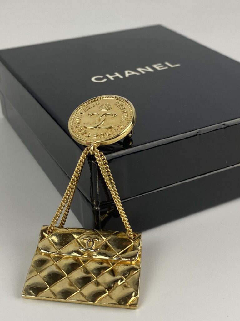 CHANEL - Broche en métal doré formée d'une pièce ornée du sigle de la marque et…