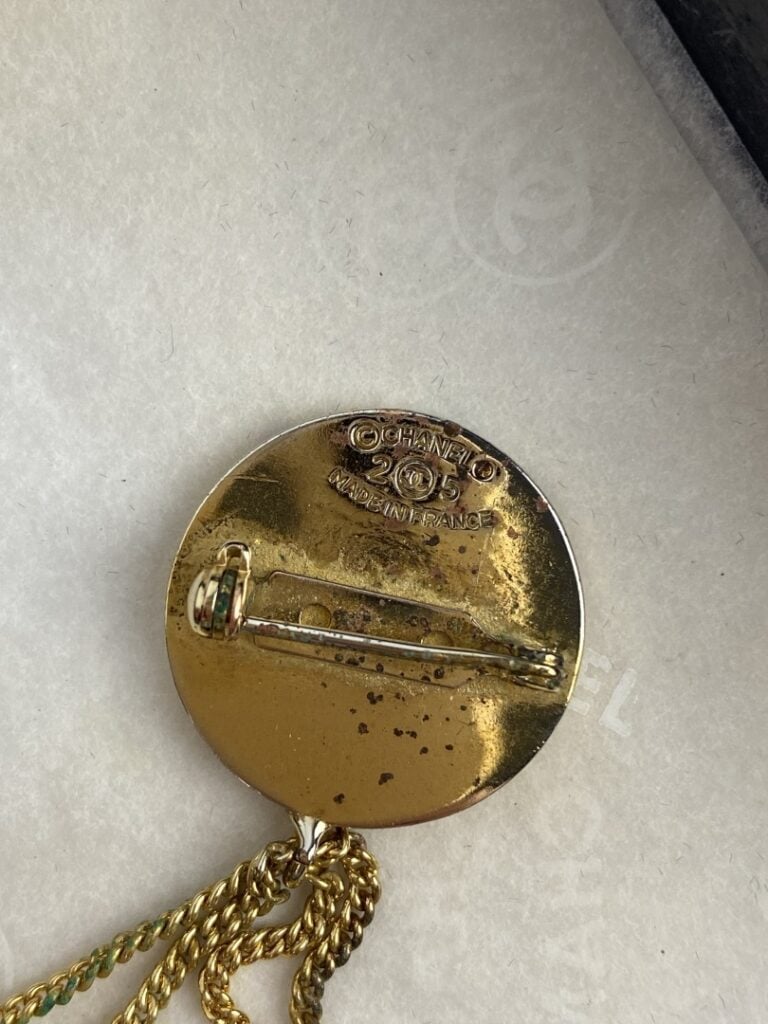 CHANEL - Broche en métal doré formée d'une pièce ornée du sigle de la marque et…