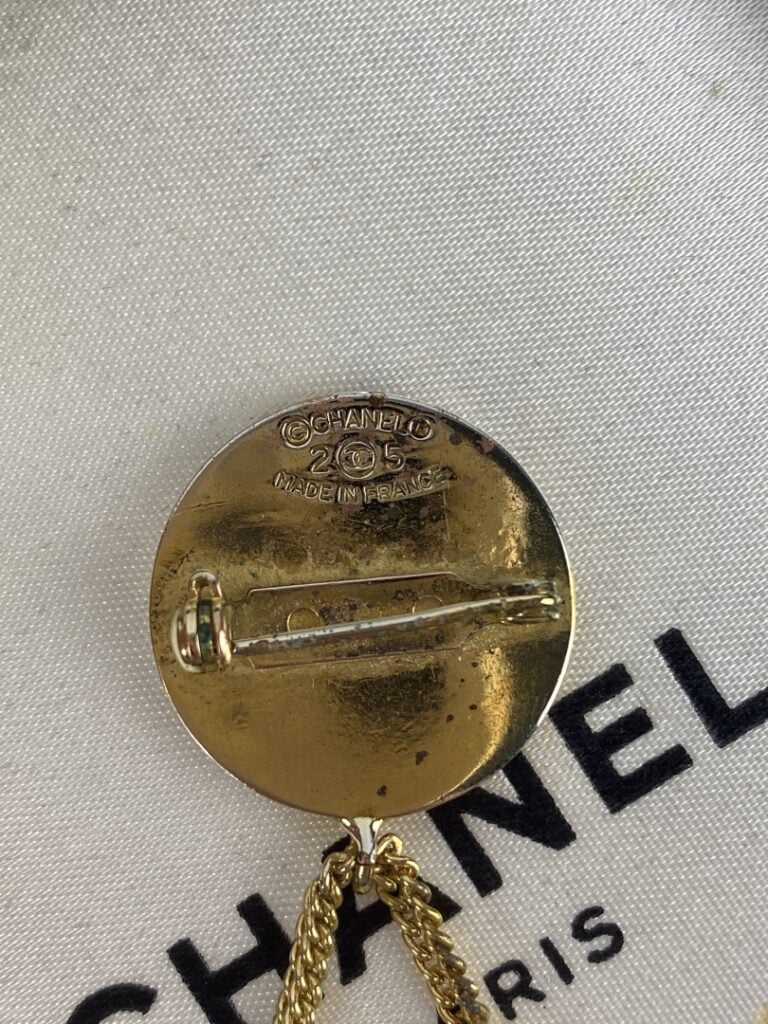 CHANEL - Broche en métal doré formée d'une pièce ornée du sigle de la marque et…