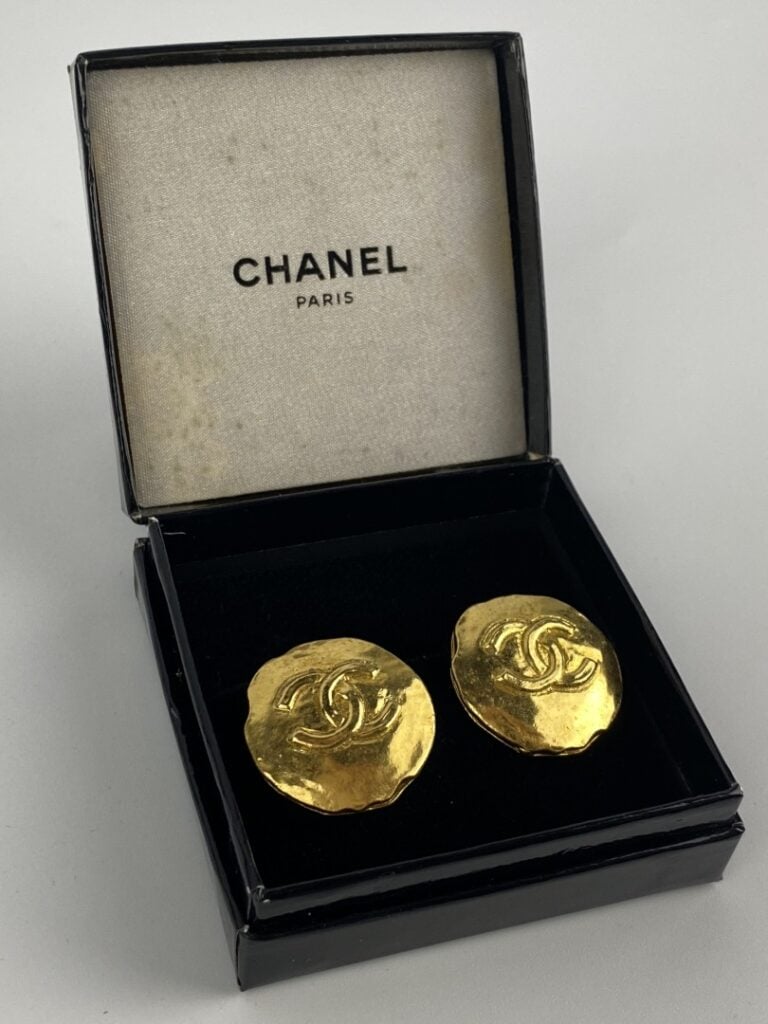 CHANEL - Paire de clips d'oreilles en métal doré légèrement martelé ornés du si…