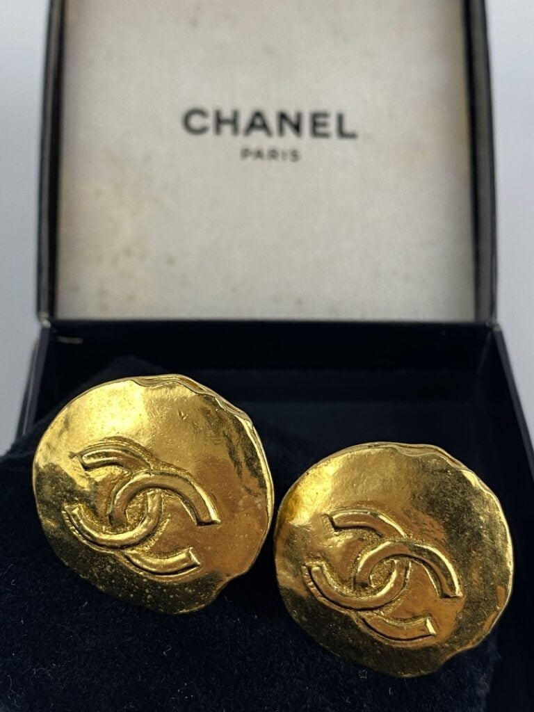 CHANEL - Paire de clips d'oreilles en métal doré légèrement martelé ornés du si…